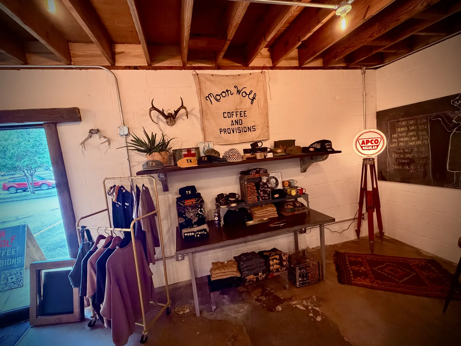 Moon Wolf retail wall with apparel, hand-painted signage, plants, and antlers.
